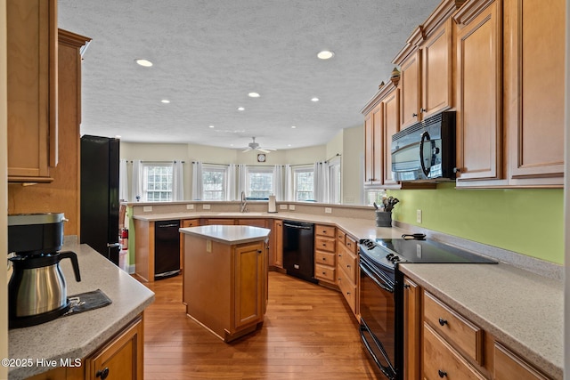 174 Banbridge Dr, West End, NC 27376 - kitchen with a peninsula, wood finished floors, light countertops, a sink, and black appliances