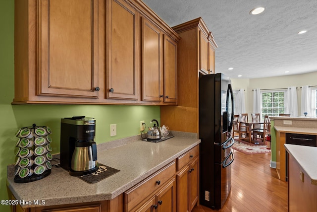 174 Banbridge Dr, West End, NC 27376 - kitchen featuring a textured ceiling, brown cabinets, wood finished floors, black fridge, and recessed lighting