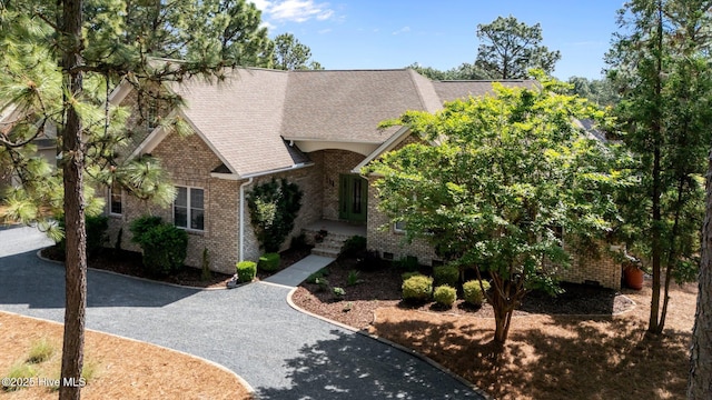 view of front of house with brick siding and roof with shingles