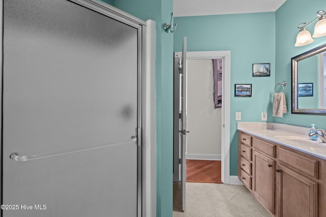bathroom featuring vanity, tile patterned floors, baseboards, and a stall shower