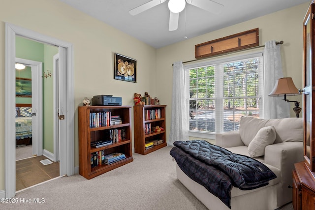 living area with baseboards, a ceiling fan, and carpet flooring