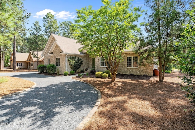 view of front of house featuring driveway, crawl space, and brick siding