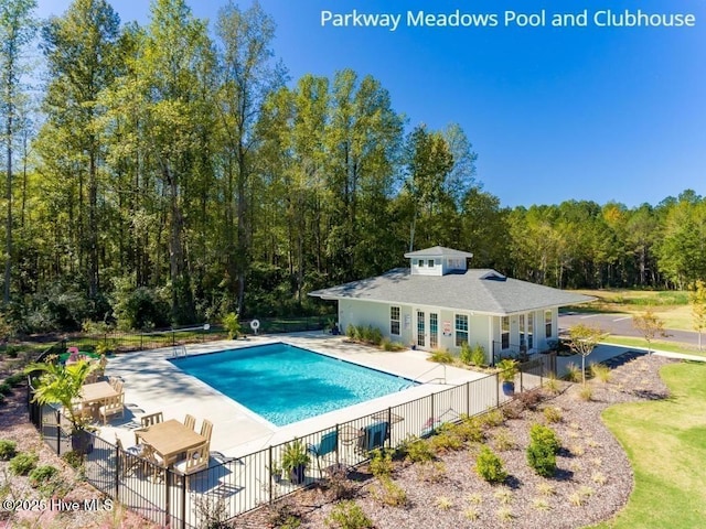 view of pool featuring a forest view, a patio area, a fenced in pool, and fence