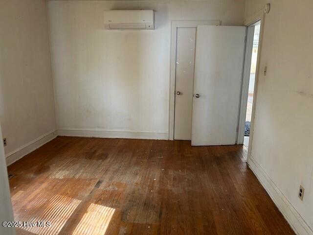 902 Johnston St, Edenton, NC 27932 - unfurnished room with baseboards, a wall unit AC, and hardwood / wood-style floors