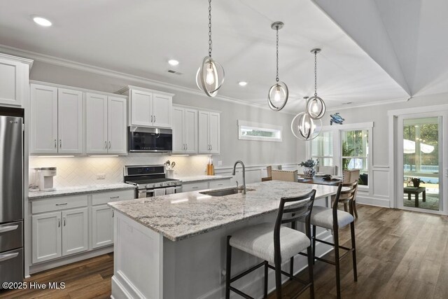 323 Lightning Bug Ln, Holly Ridge, NC 28445 - kitchen with stainless steel appliances, a sink, a breakfast bar area, a kitchen island with sink, and decorative backsplash