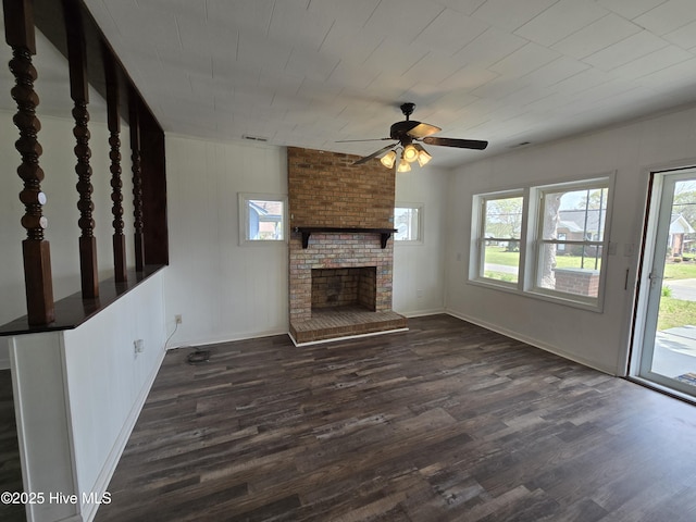 117 Flowers St, Rockingham, NC 28379 - unfurnished living room featuring a brick fireplace, a healthy amount of sunlight, ceiling fan, and dark wood-style flooring