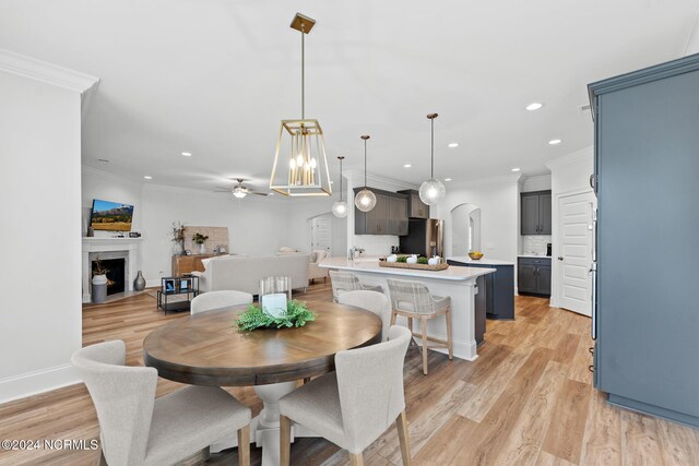 dining room with a high end fireplace, crown molding, light wood-style floors, and recessed lighting