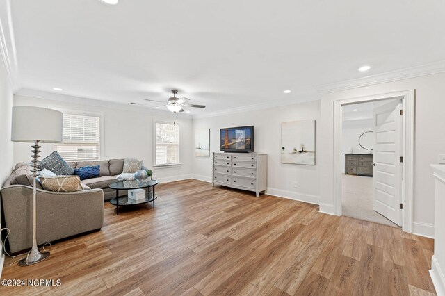 living area with baseboards, ornamental molding, a ceiling fan, and light wood finished floors