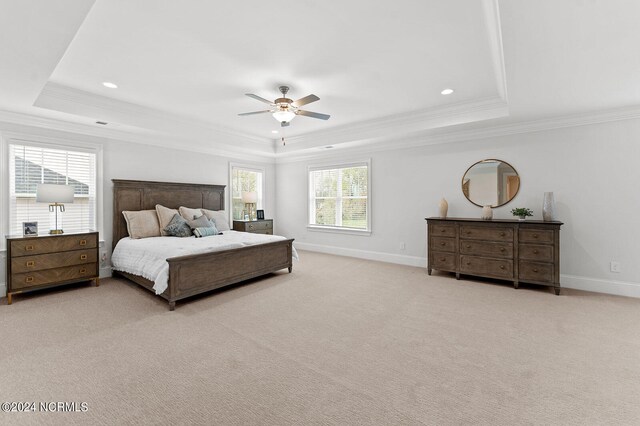 bedroom featuring a tray ceiling, crown molding, recessed lighting, baseboards, and light carpet