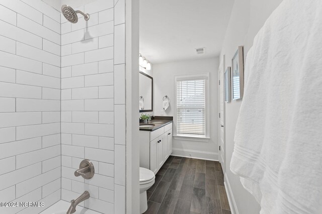 full bath with toilet, bathing tub / shower combination, vanity, wood finish floors, and visible vents