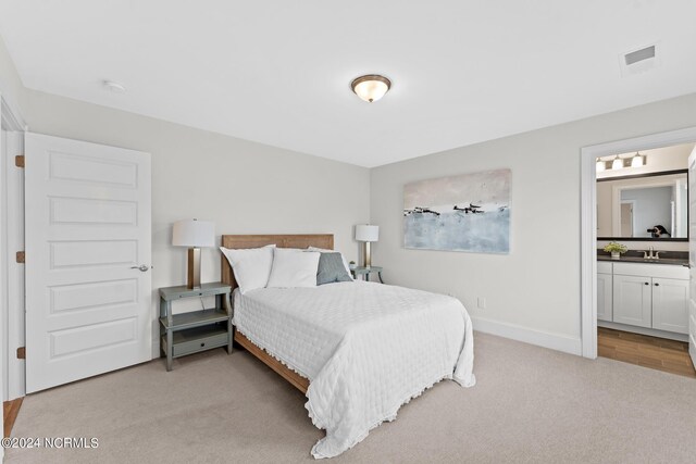 bedroom featuring visible vents, baseboards, connected bathroom, light carpet, and a sink