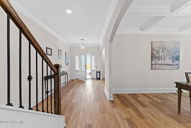 entrance foyer with arched walkways, baseboards, stairway, and light wood finished floors