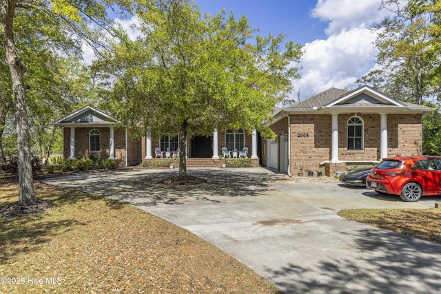 view of front of property with a porch, an attached garage, brick siding, and concrete driveway