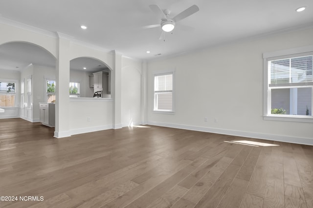1008 Peace St Lot 69, Leland, NC 28451 - unfurnished living room with ornamental molding, wood finished floors, arched walkways, plenty of natural light, and a ceiling fan