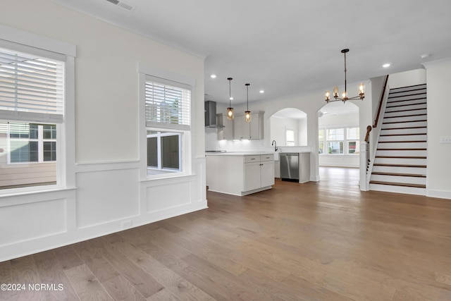 1008 Peace St Lot 69, Leland, NC 28451 - kitchen featuring stainless steel dishwasher, wall chimney range hood, wood finished floors, arched walkways, and light countertops