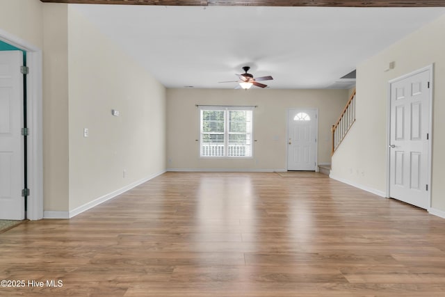 318 Winchester Way, Merritt, NC 28556 - unfurnished living room with baseboards, a ceiling fan, stairs, and light wood-type flooring