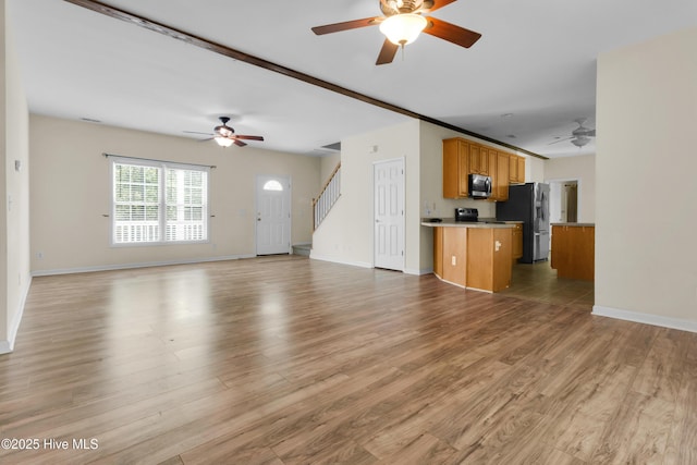 318 Winchester Way, Merritt, NC 28556 - unfurnished living room with stairway, ceiling fan, baseboards, and light wood finished floors