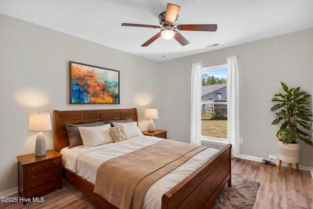 bedroom featuring light wood-type flooring, ceiling fan, baseboards, and visible vents