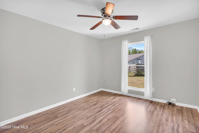 unfurnished room with visible vents, baseboards, ceiling fan, and wood finished floors