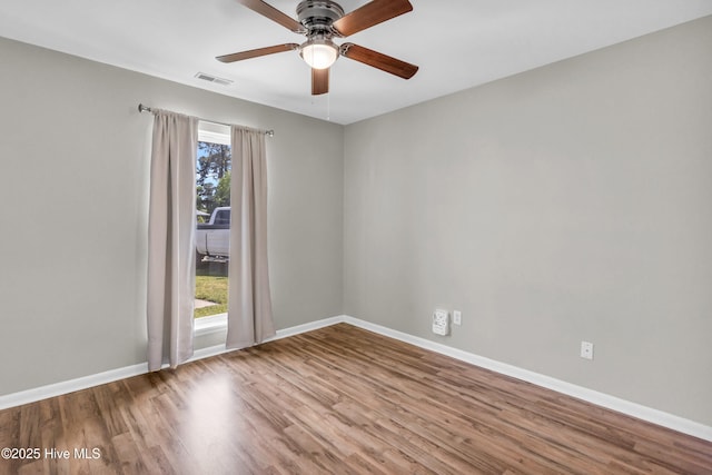 spare room with wood finished floors, baseboards, a ceiling fan, and visible vents