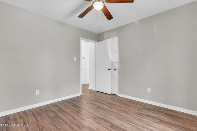empty room with wood finished floors, baseboards, and a ceiling fan