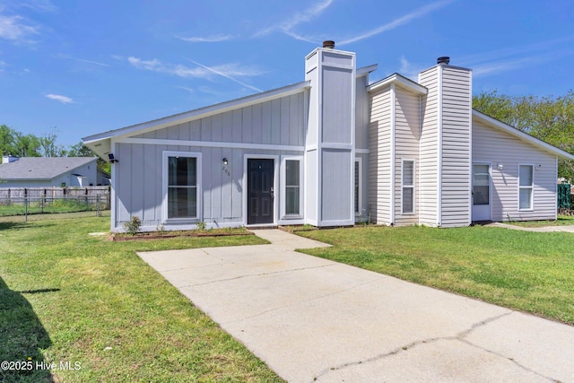 rear view of property featuring a yard, fence, board and batten siding, and a chimney