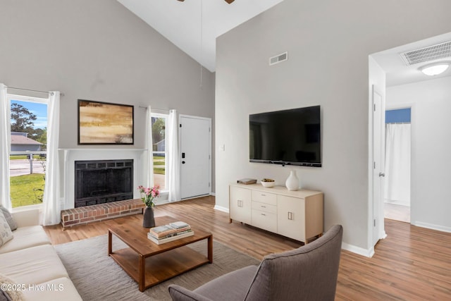 living room featuring high vaulted ceiling, baseboards, and visible vents