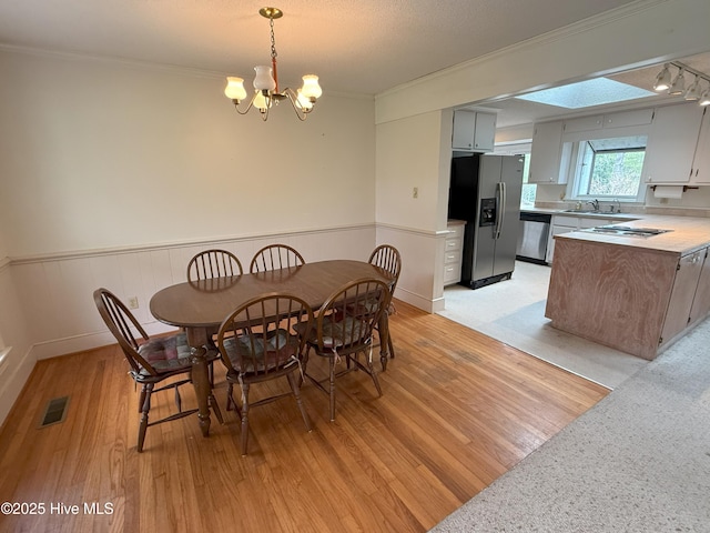114 Long Leaf Ln, Plymouth, NC 27962 - dining space with light wood-style flooring, wainscoting, visible vents, a chandelier, and crown molding