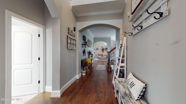 hall with baseboards, arched walkways, ornamental molding, and dark wood-style flooring