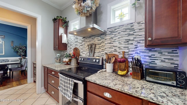 kitchen with ornamental molding, a healthy amount of sunlight, double oven range, wall chimney range hood, and light tile patterned floors