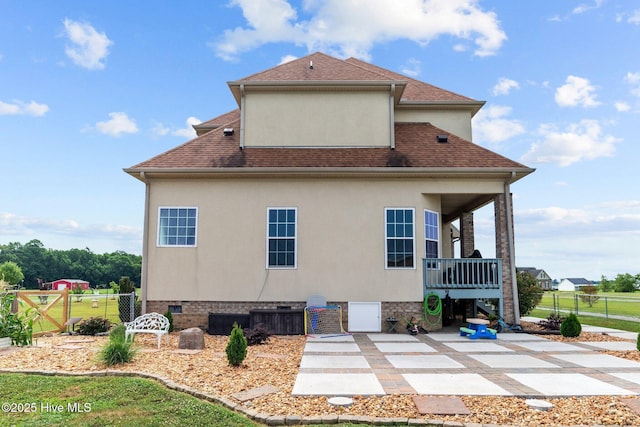 rear view of house with stucco siding, crawl space, a shingled roof, and fence