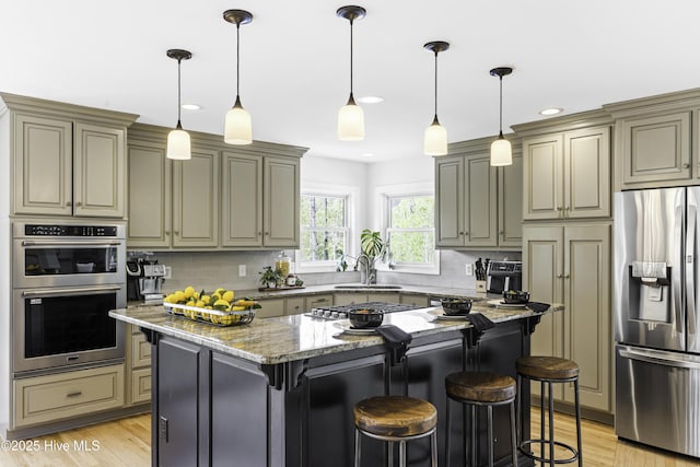 8050 Rachel Wynd Rd NE, Leland, NC 28451 - kitchen with light stone countertops, light wood-style flooring, stainless steel appliances, decorative backsplash, and a kitchen bar