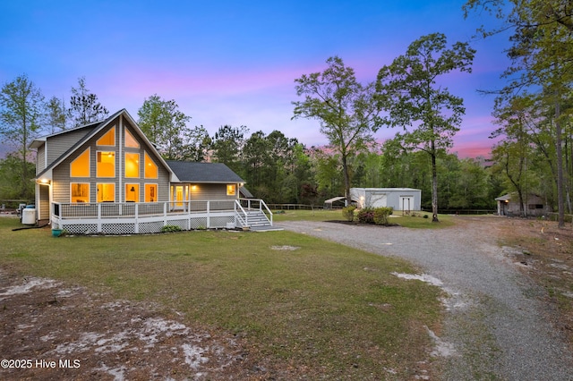 8050 Rachel Wynd Rd NE, Leland, NC 28451 - back of property at dusk featuring a lawn, a deck, and gravel driveway