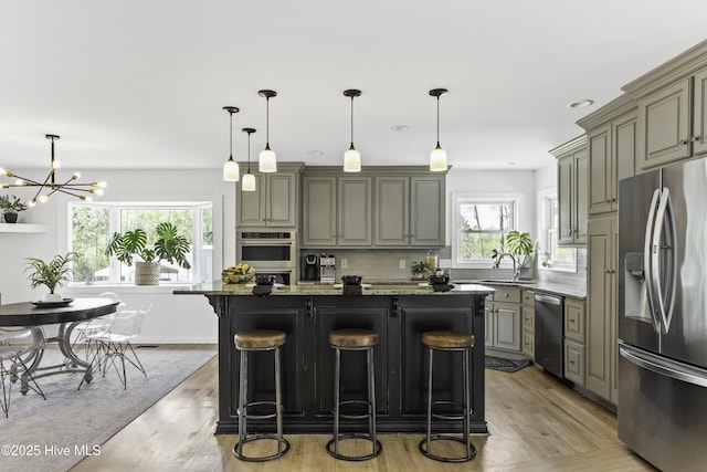 8050 Rachel Wynd Rd NE, Leland, NC 28451 - kitchen featuring a kitchen island, a kitchen bar, tasteful backsplash, light wood finished floors, and appliances with stainless steel finishes