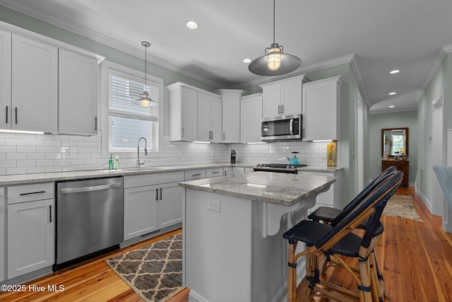 15 Station Ave, Southern Pines, NC 28387 - kitchen featuring stainless steel appliances, light wood-style flooring, a sink, and ornamental molding