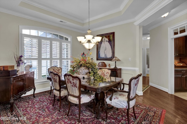 9278 Checkerberry Sq NW, Calabash, NC 28467 - dining area featuring a chandelier, wood finished floors, a tray ceiling, and ornamental molding