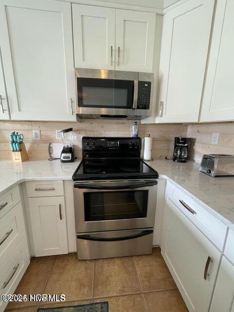 790 New River Inlet Rd Unit 208B, North Topsail Beach, NC 28460 - kitchen featuring light tile patterned flooring, stainless steel appliances, tasteful backsplash, white cabinetry, and light stone counters