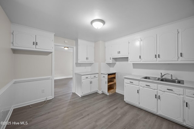 705 W Main St, Conway, NC 27820 - kitchen with a sink, white cabinetry, wood finished floors, light countertops, and a wainscoted wall