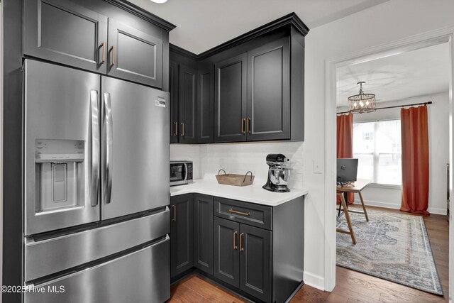 kitchen featuring backsplash, light countertops, appliances with stainless steel finishes, and wood finished floors