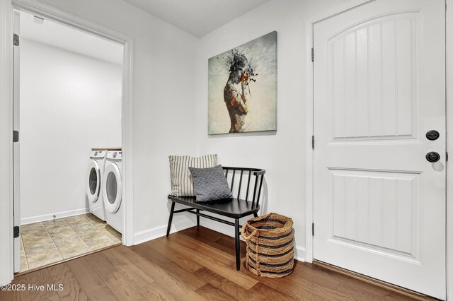washroom featuring washer and dryer, laundry area, wood finished floors, and baseboards