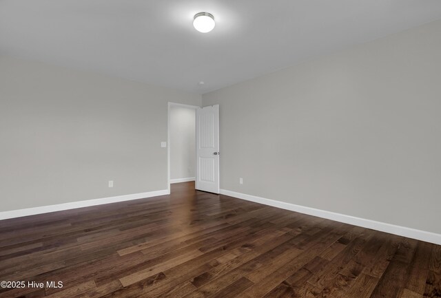 spare room featuring dark wood-style flooring and baseboards