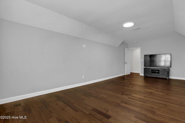 unfurnished living room with wood finished floors, baseboards, and lofted ceiling