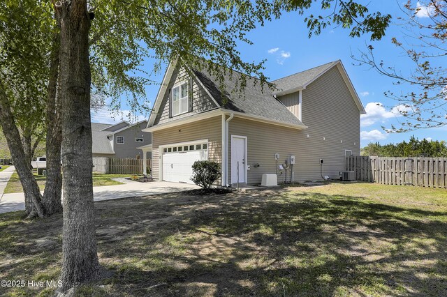 view of home's exterior featuring central AC unit, a shingled roof, a garage, fence, and concrete driveway