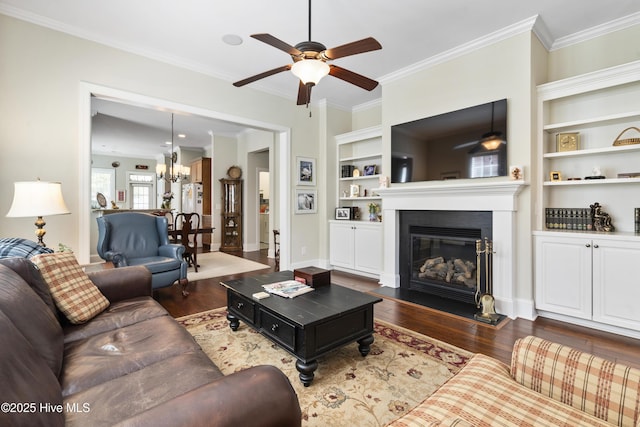 1502 Crows Landing Cir, Wilmington, NC 28403 - living room featuring a ceiling fan, dark wood finished floors, a glass covered fireplace, crown molding, and built in shelves