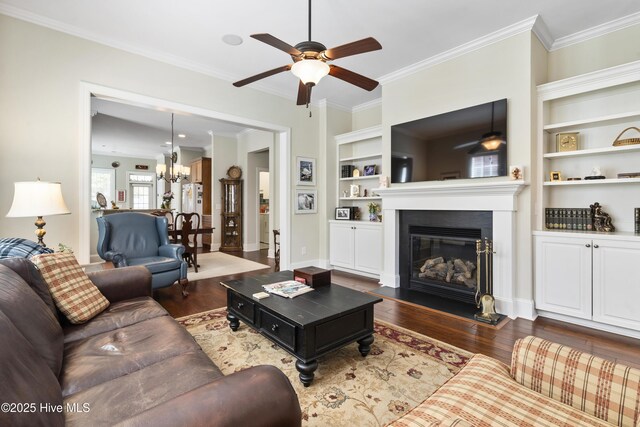 1502 Crows Landing Cir, Wilmington, NC 28403 - living room featuring a ceiling fan, dark wood finished floors, a glass covered fireplace, crown molding, and built in shelves