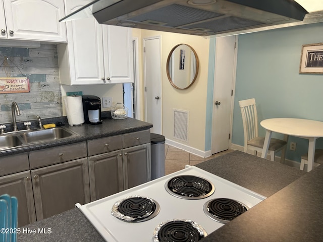 kitchen with dark countertops, extractor fan, visible vents, a sink, and light tile patterned flooring