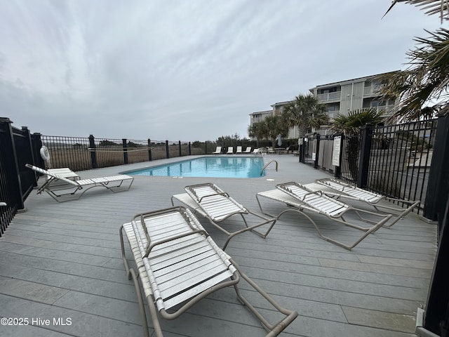 community pool with a wooden deck and fence