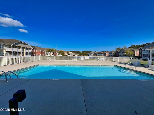 community pool featuring fence, a residential view, and a patio