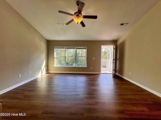 unfurnished room featuring plenty of natural light, a ceiling fan, dark wood finished floors, and baseboards