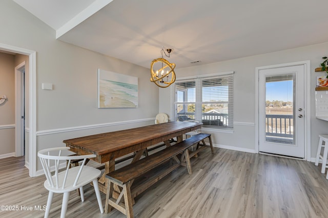 dining room with a chandelier, light wood-style flooring, baseboards, and visible vents